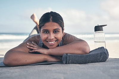 Buy stock photo Shot of a sporty young woman lying on her yoga mat at the beach
