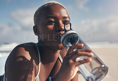 Buy stock photo Shot of a sporty young woman drinking water while out for a workout