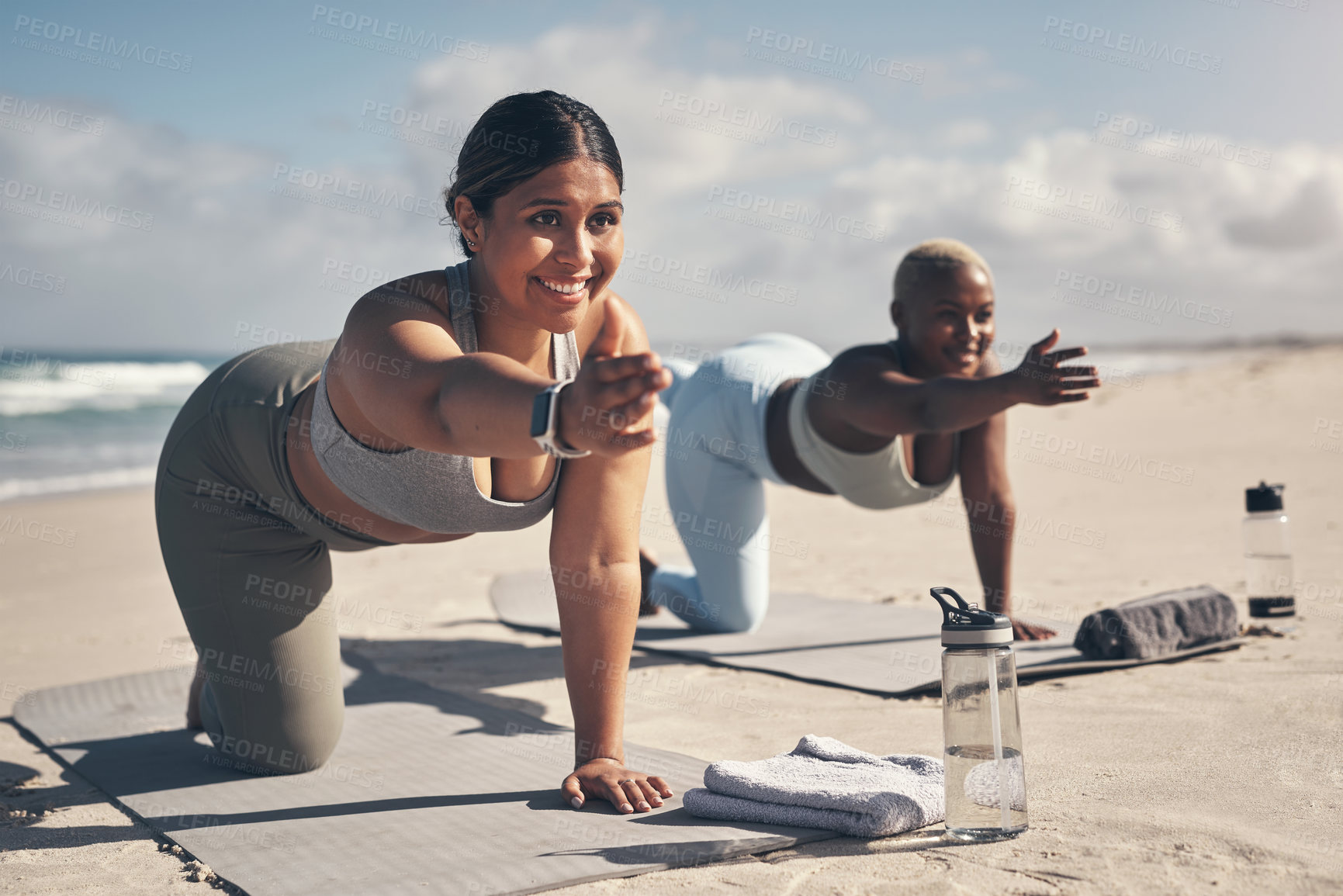 Buy stock photo Shot of two young women practicing yoga on the beach