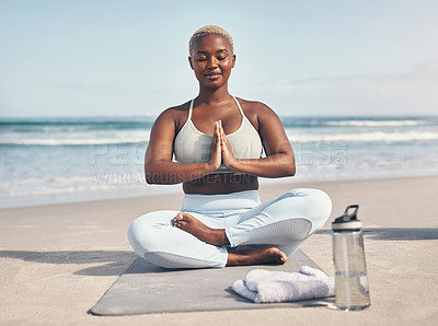 Buy stock photo Shot of a woman meditating during her yoga routine on the beach