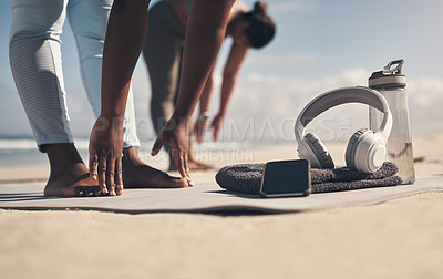 Buy stock photo Shot of two young women stretching on the beach