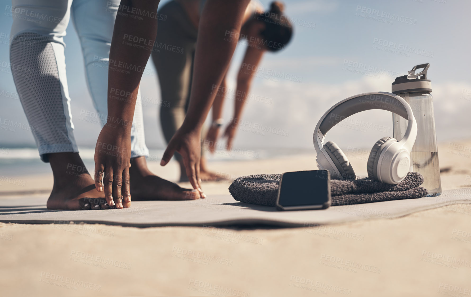 Buy stock photo Shot of two young women stretching on the beach