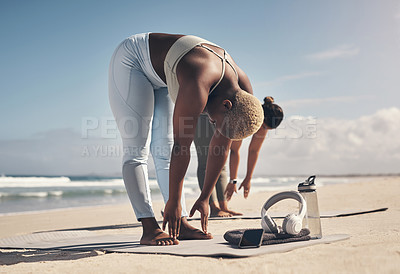 Buy stock photo Shot of two young women stretching on the beach