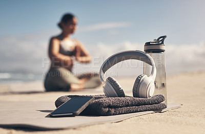 Buy stock photo Shot of a cellphone, headphones, towel and water bottle on the beach