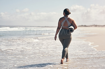 Buy stock photo Rearview shot of a woman walking on the beach with her yoga mat