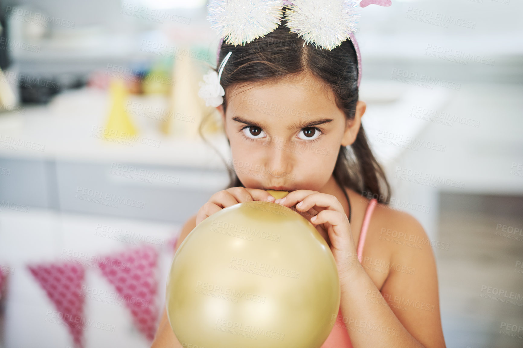 Buy stock photo Shot of an adorable little girl blowing up a balloon at her birthday party