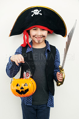 Buy stock photo Shot of a little boy dressed in a pirate costume while holding a jack o lantern against a white background