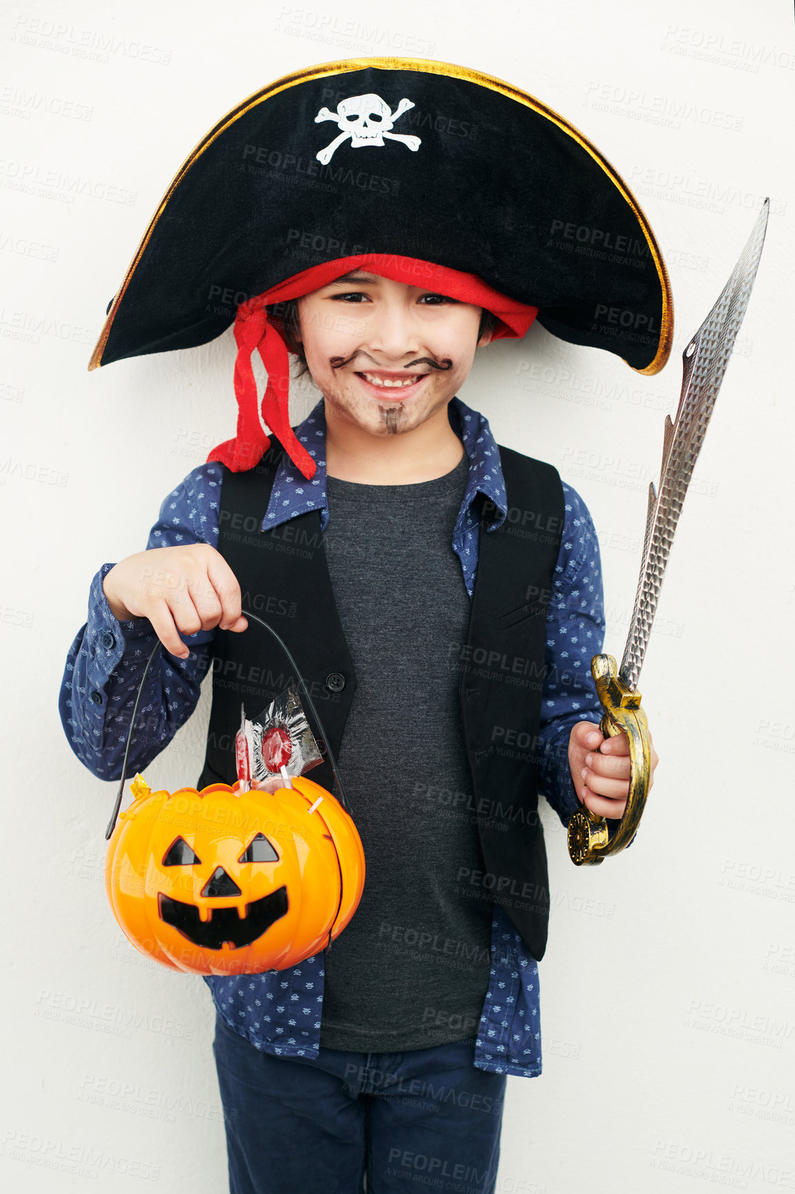 Buy stock photo Shot of a little boy dressed in a pirate costume while holding a jack o lantern against a white background