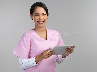 Buy stock photo Cropped portrait of an attractive young female healthcare worker using a tablet in studio against a grey background