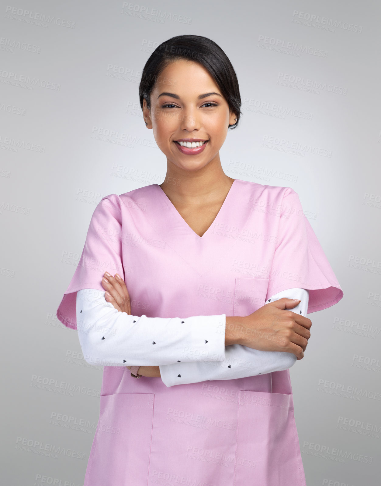 Buy stock photo Cropped portrait of an attractive young female healthcare worker standing with her arms crossed in studio against a grey background