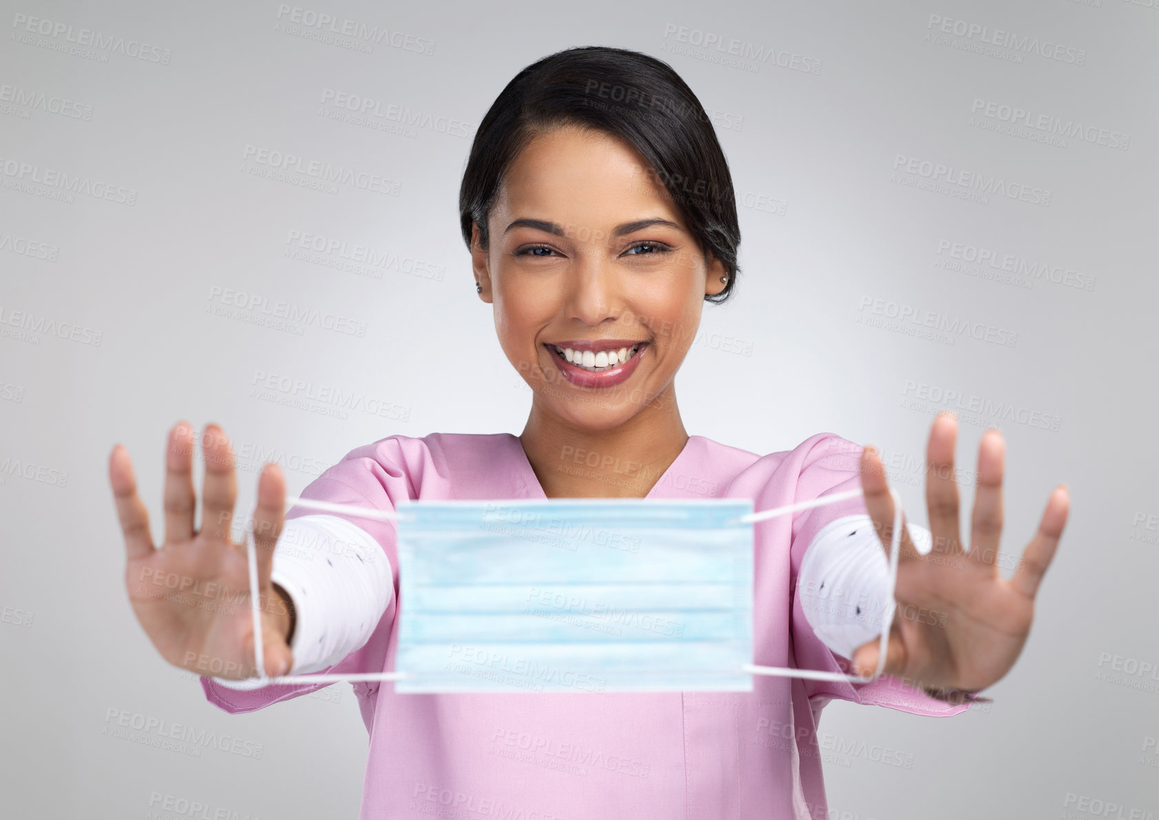 Buy stock photo Cropped portrait of an attractive young female healthcare worker holding up a mask in studio against a grey background