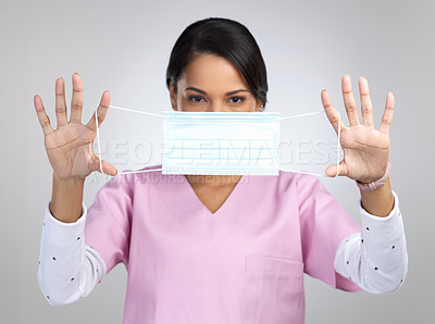 Buy stock photo Cropped portrait of an attractive young female healthcare worker holding up a mask in studio against a grey background