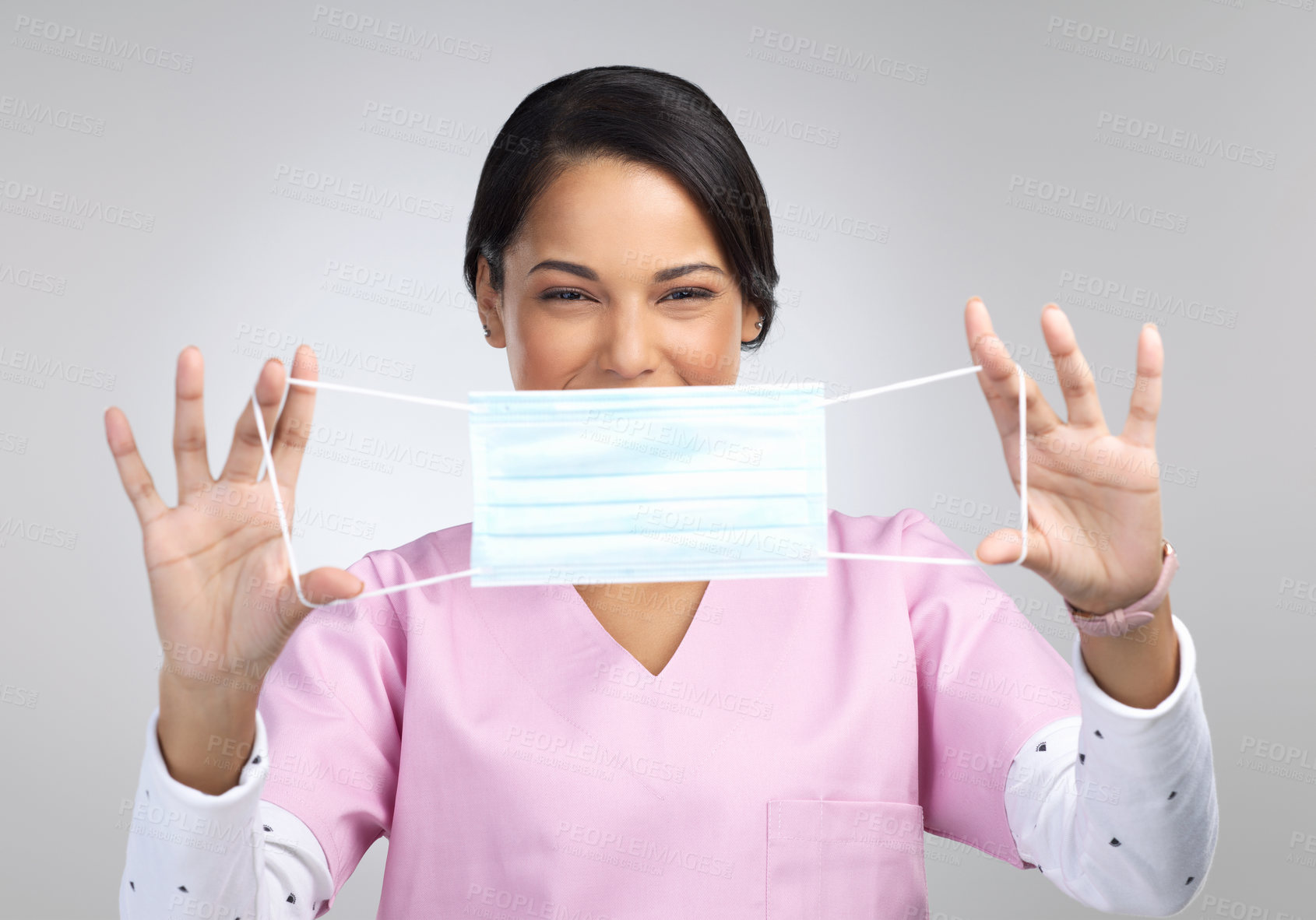 Buy stock photo Cropped portrait of an attractive young female healthcare worker holding up a mask in studio against a grey background