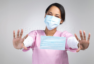 Buy stock photo Cropped portrait of an attractive young female healthcare worker holding up a mask in studio against a grey background