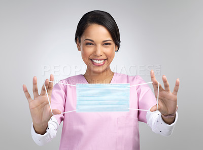 Buy stock photo Cropped portrait of an attractive young female healthcare worker holding up a mask in studio against a grey background