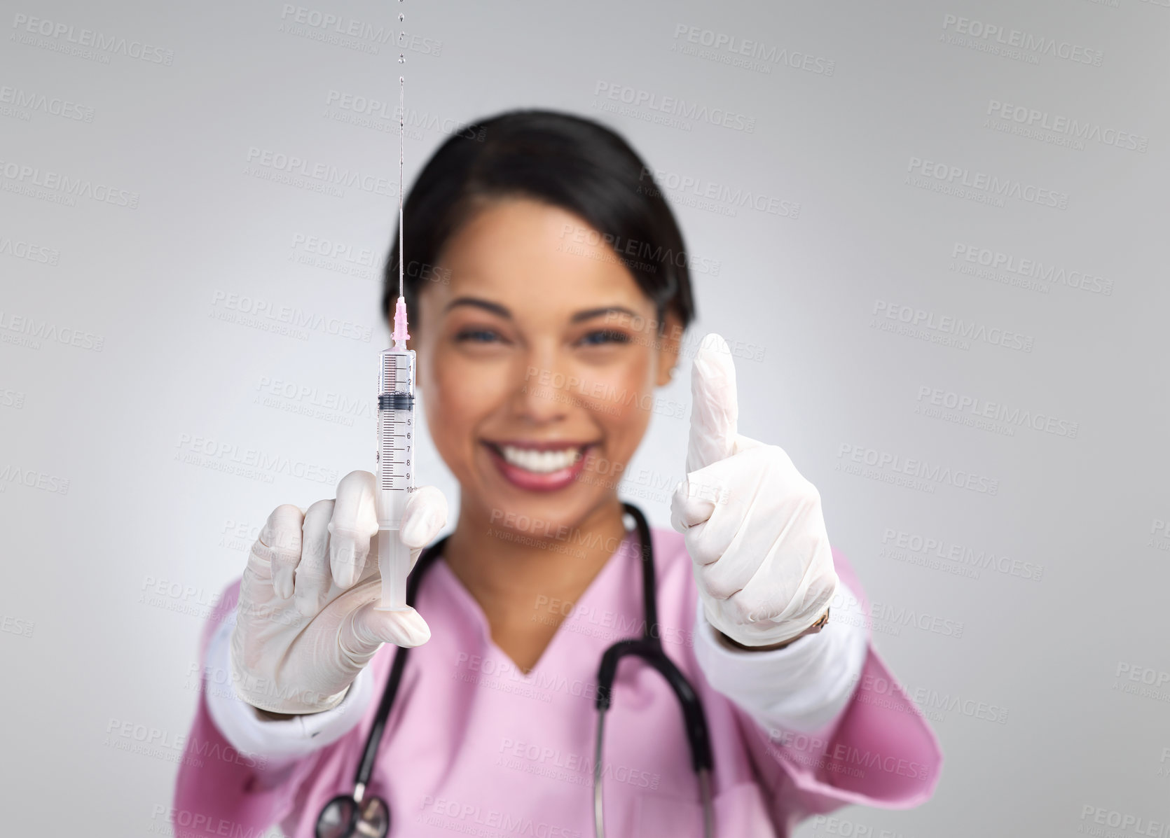 Buy stock photo Cropped portrait of an attractive young female healthcare working holding up a syringe and gesturing thumbs up in studio against a grey background