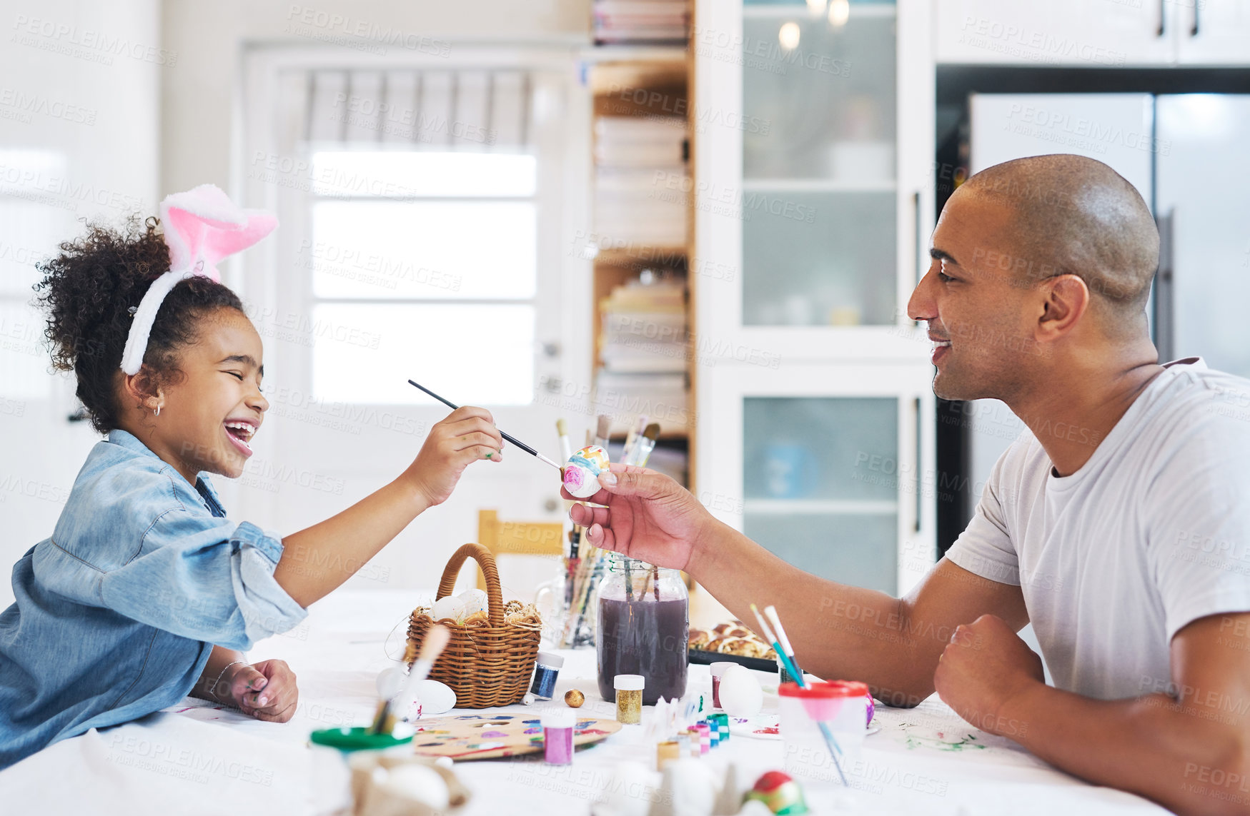 Buy stock photo Shot of a man painting eggs with his daughter at home