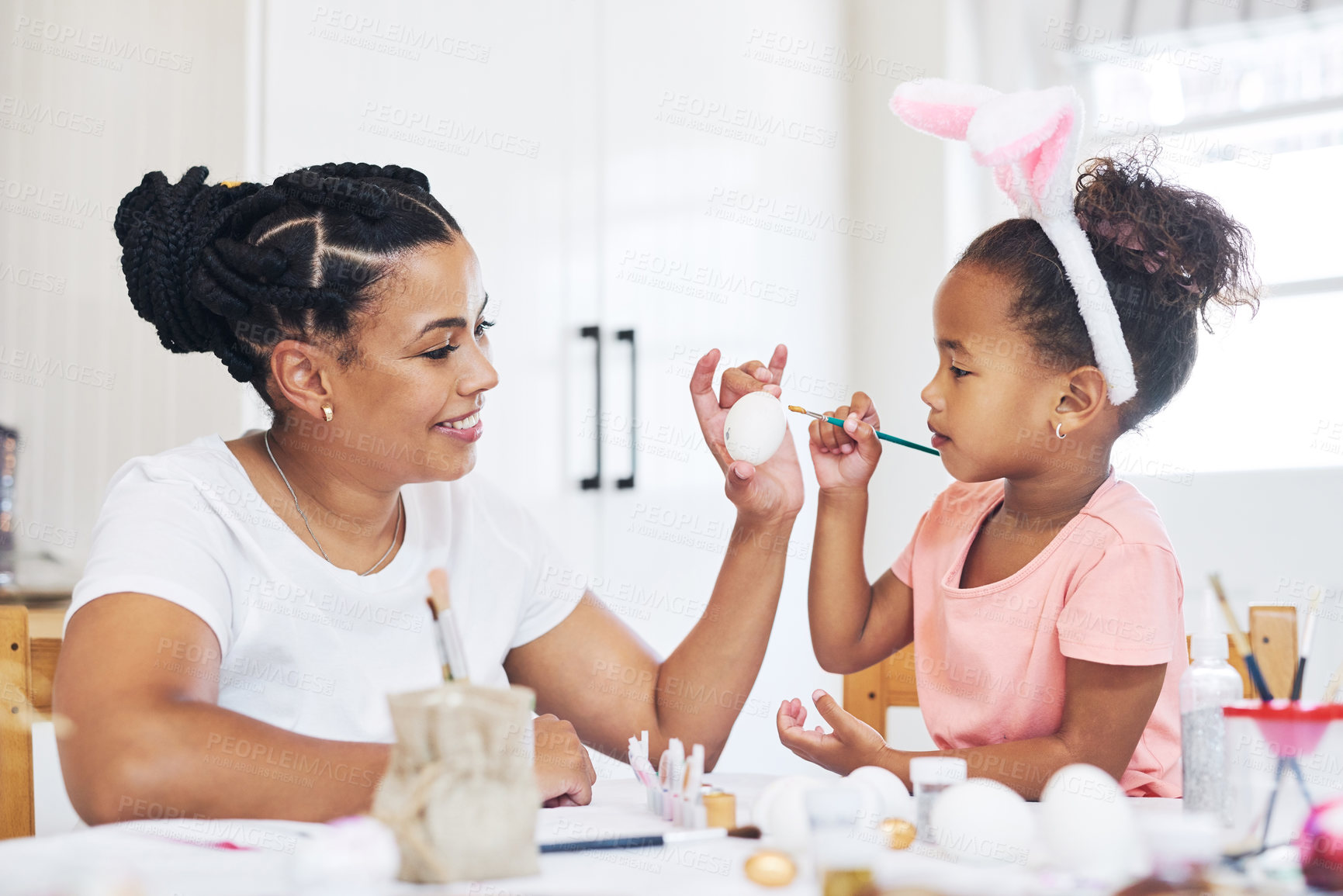 Buy stock photo Shot of a female painting eggs with her daughter at home