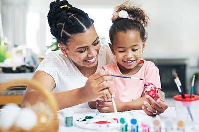 Buy stock photo Shot of a female painting eggs with her daughter at home