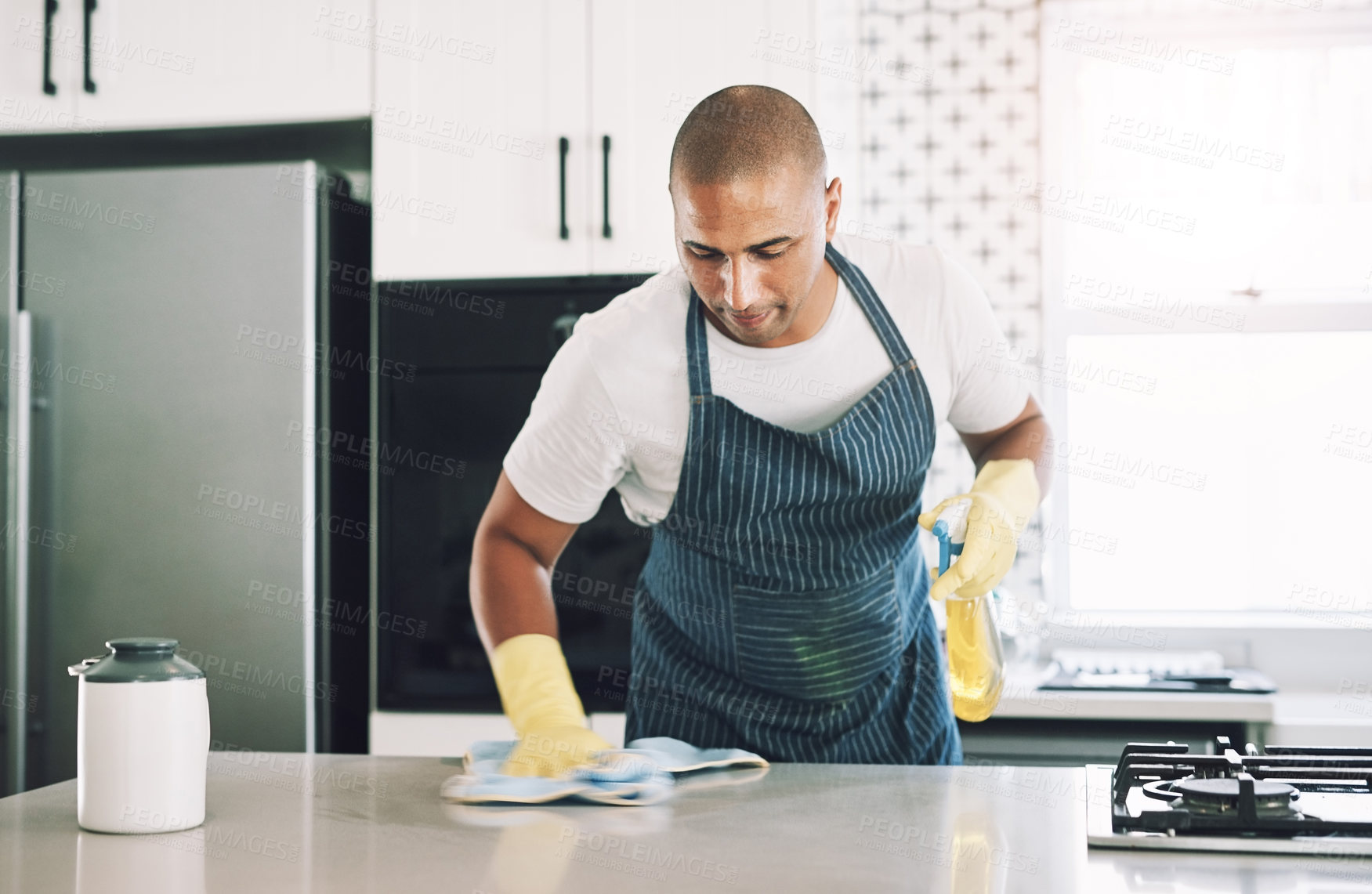 Buy stock photo Shot of a young man wiping a surface at home