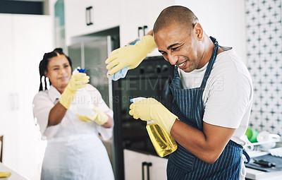 Buy stock photo shot of a young couple being playful while cleaning at home