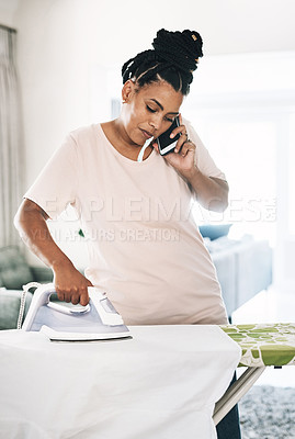 Buy stock photo Shot of a young woman ironing clothes while on the phone at home