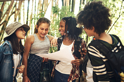 Buy stock photo Shot of a group of teenagers looking at a map while exploring nature together at summer camp