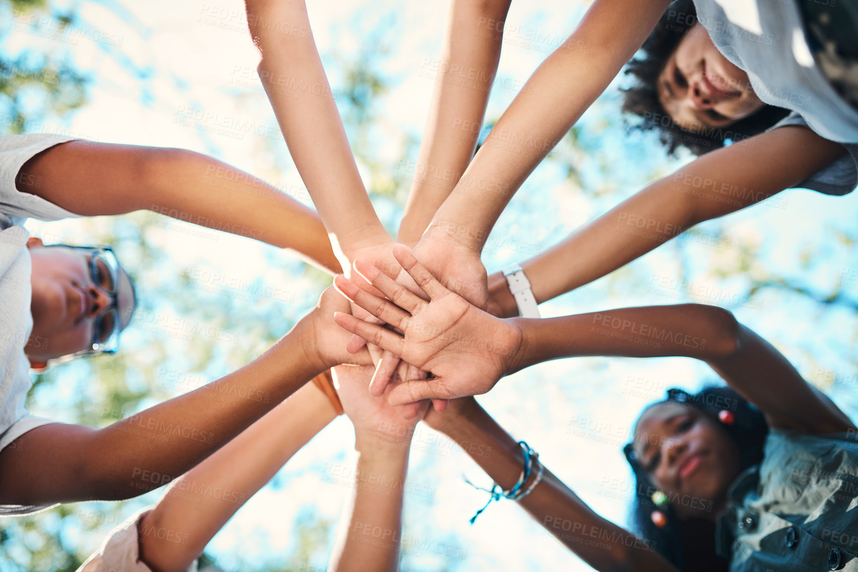 Buy stock photo Shot of a group of teenagers standing in a circle and joining their hands in solidarity at summer camp