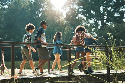 Buy stock photo Shot of a group of teenagers walking across a bridge in nature at summer camp