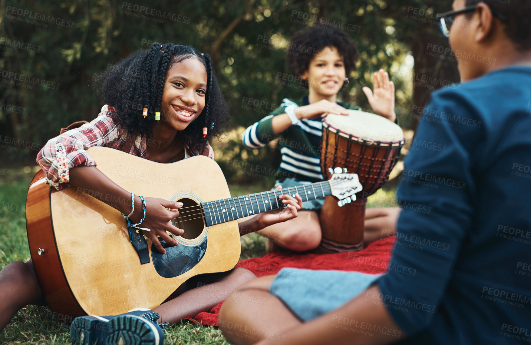 Buy stock photo Shot of a group of teenagers playing musical instruments in nature at summer camp