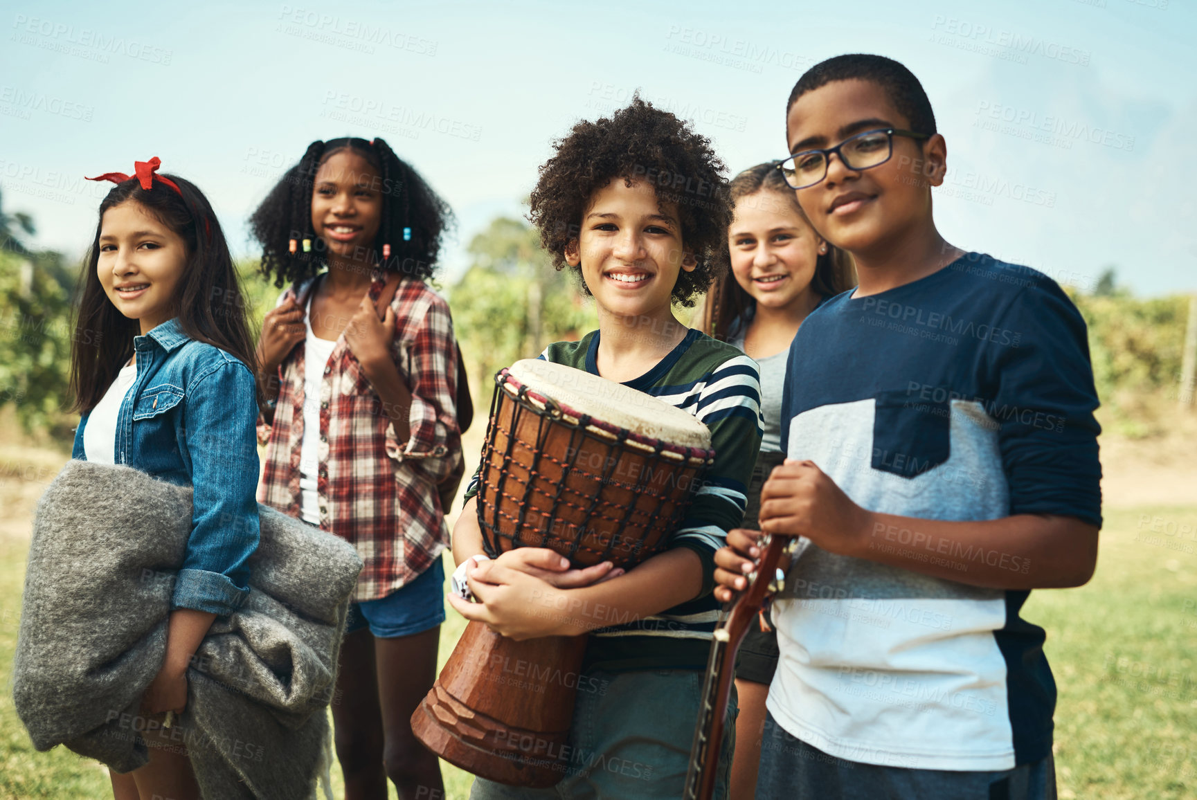 Buy stock photo Shot of a group of teenagers playing musical instruments in nature at summer camp