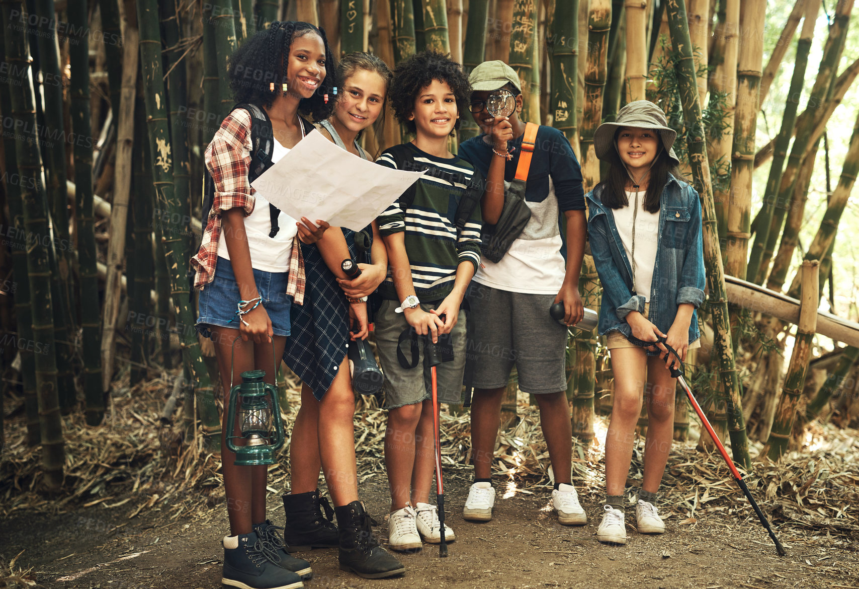 Buy stock photo Shot of a group of teenagers looking at a map while exploring nature together at summer camp