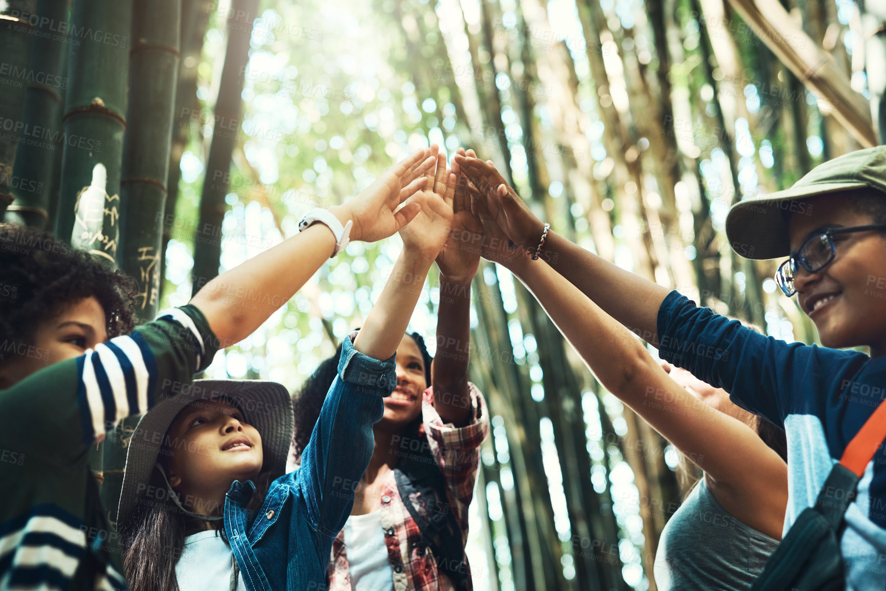 Buy stock photo Shot of a group of teenagers giving each other a high five at summer camp