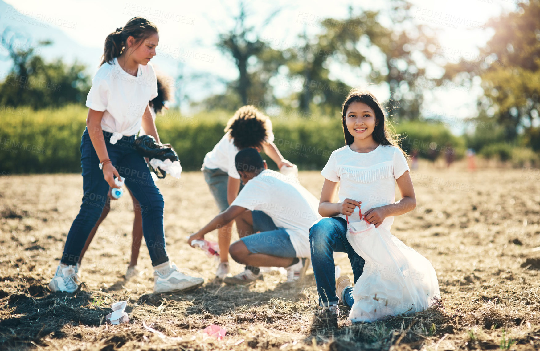 Buy stock photo Shot of a group of teenagers picking up litter off a field at summer camp