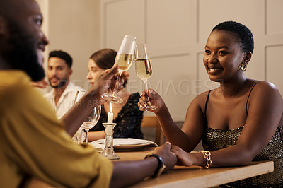 Buy stock photo Shot of a happy young couple sitting with friends and toasting with champagne during a New Year's dinner party