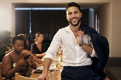 Buy stock photo Shot of a handsome young man standing and holding his jacket during a New Year's dinner party with friends