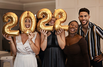 Buy stock photo Shot of a diverse group of friends standing together and holding up 2022 balloons during a New Year's party