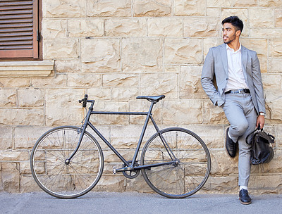 Buy stock photo Shot of a young businessman standing with a bag and a bike in the city