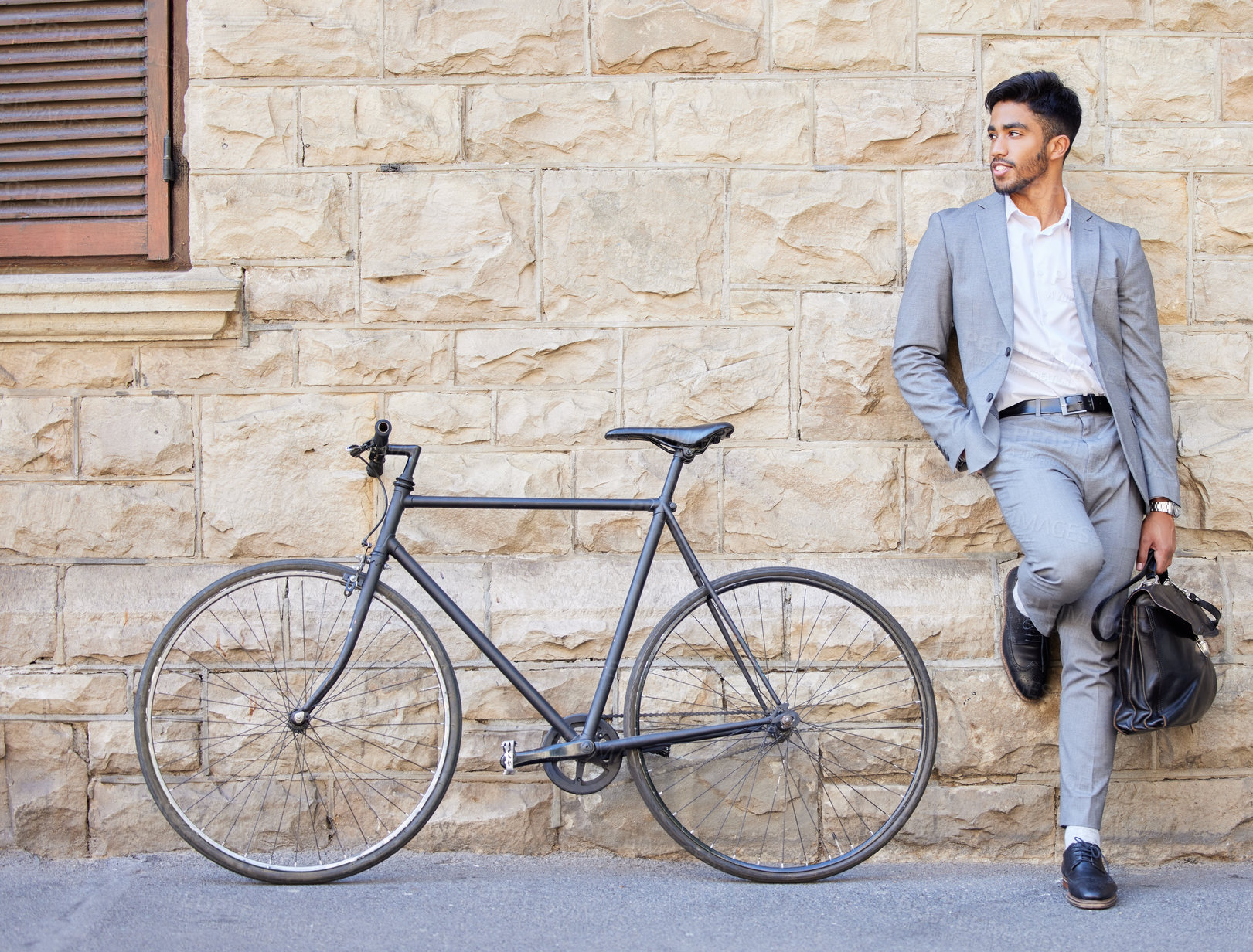 Buy stock photo Shot of a young businessman standing with a bag and a bike in the city