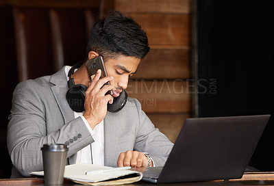 Buy stock photo Shot of a young businessman checking the time while using a phone at a cafe