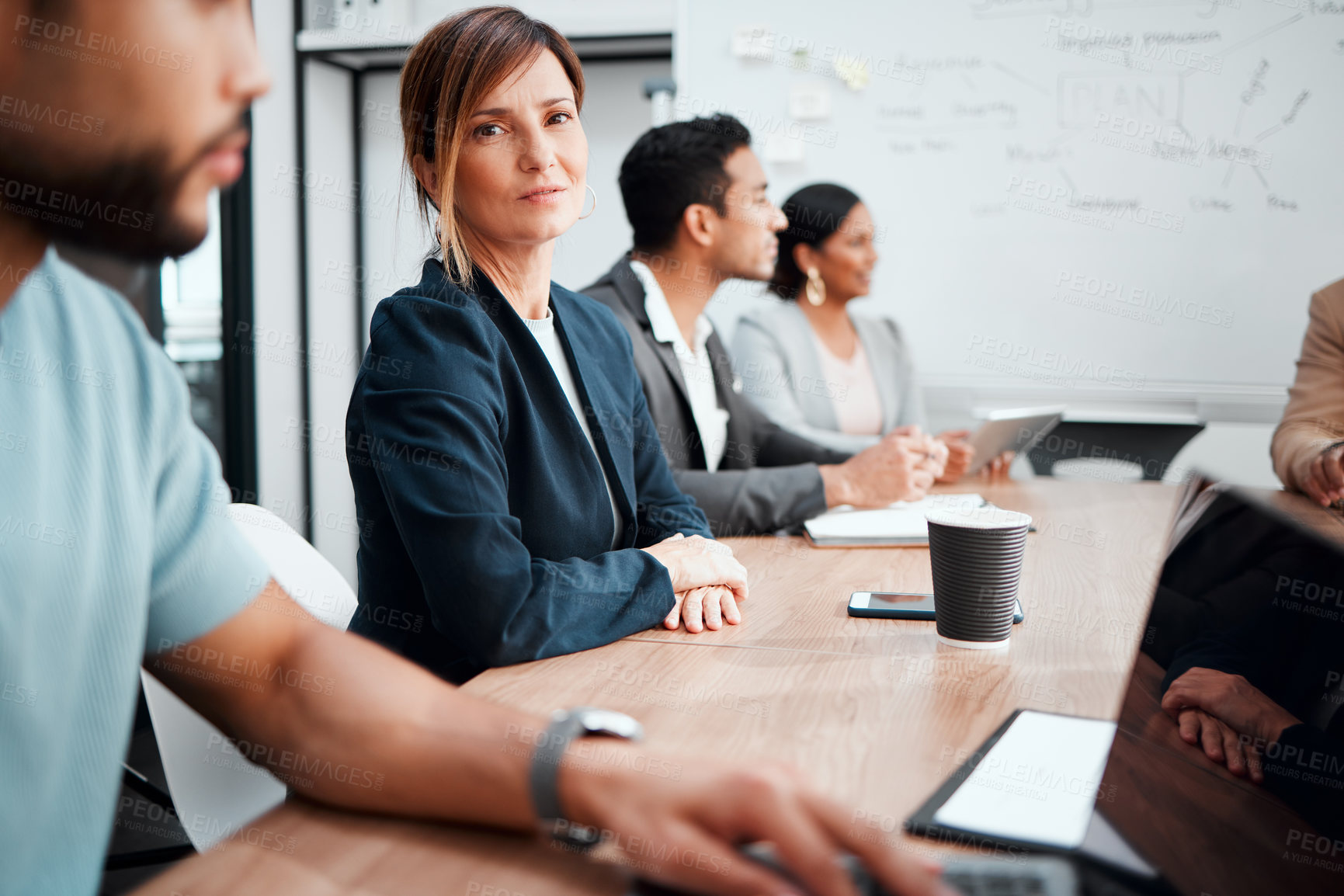 Buy stock photo Cropped portrait of an attractive young businesswoman sitting at the boardroom table during a meeting with her colleagues