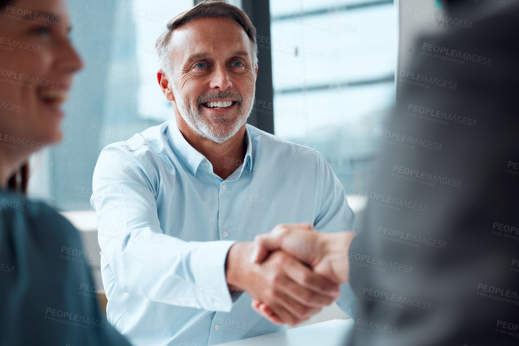 Buy stock photo Shot of a mature businessman shaking hands with a colleague during a meeting in an office