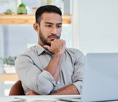 Buy stock photo Shot of a young businessman using his laptop