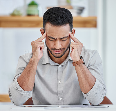 Buy stock photo Shot of a young businessman experiencing a headache while at work