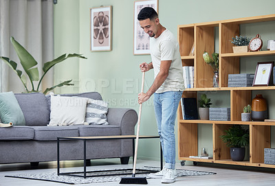 Buy stock photo Shot of a young man sweeping the floor at home