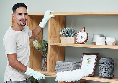 Buy stock photo Shot of a young man dusting a shelf at home