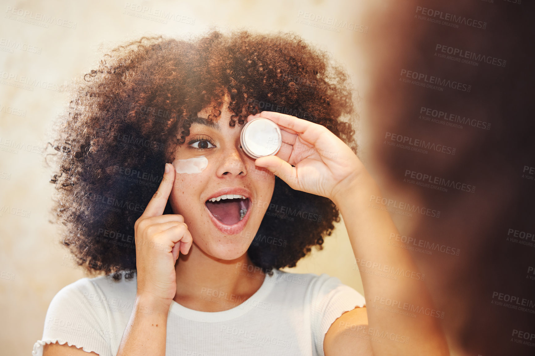 Buy stock photo Shot of a beautiful young woman applying moisturiser to her face