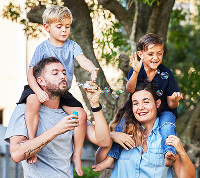 Buy stock photo Couple, children and love with bubbles in park for happy relationship, learning and family time. Parents, kids and portrait in outdoor for relax together with development, safe and soap toy by tree