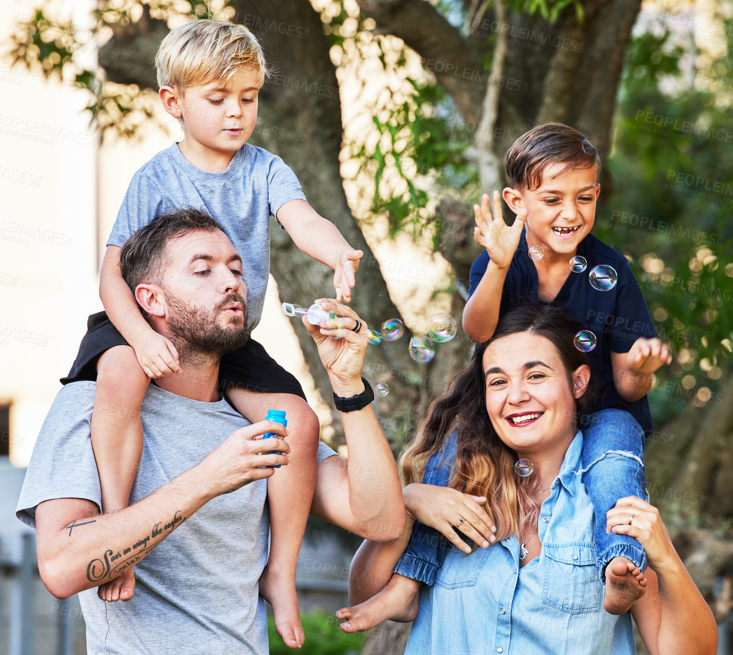 Buy stock photo Couple, children and love with bubbles in park for happy relationship, learning and family time. Parents, kids and portrait in outdoor for relax together with development, safe and soap toy by tree