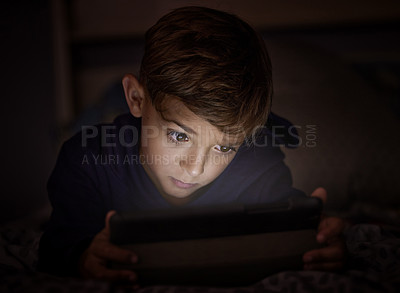 Buy stock photo Shot of adorable little boy using a digital tablet at night